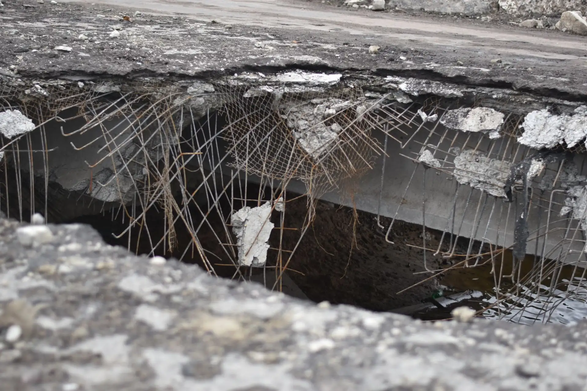Broken concrete over a void where the base beneath the slab has washed out