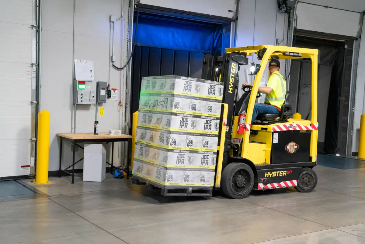 Forklift carrying a pallet across a warehouse concrete floor