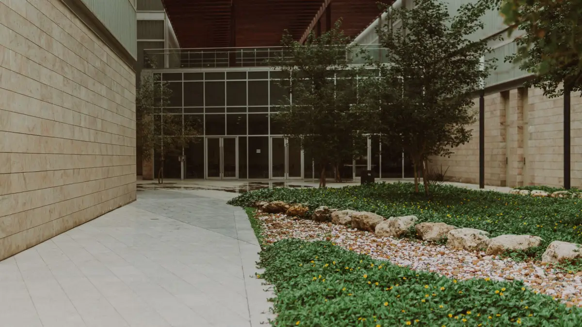 Concrete walkway running alongside a commercial building through landscaped beds