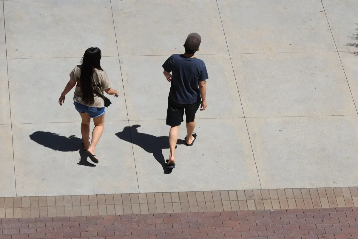 Two people walking across a wide concrete plaza