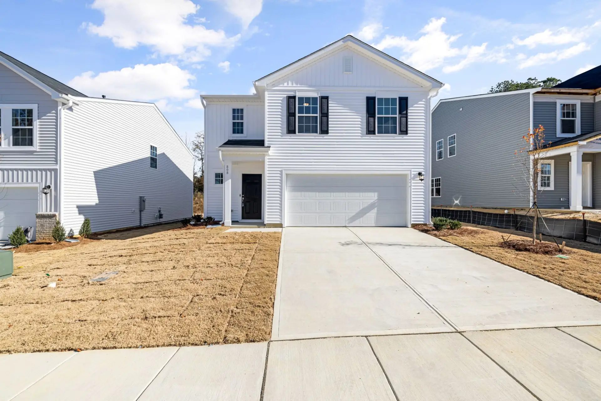 Newly poured concrete driveway and front walk at a recently built home, with the yard still bare soil