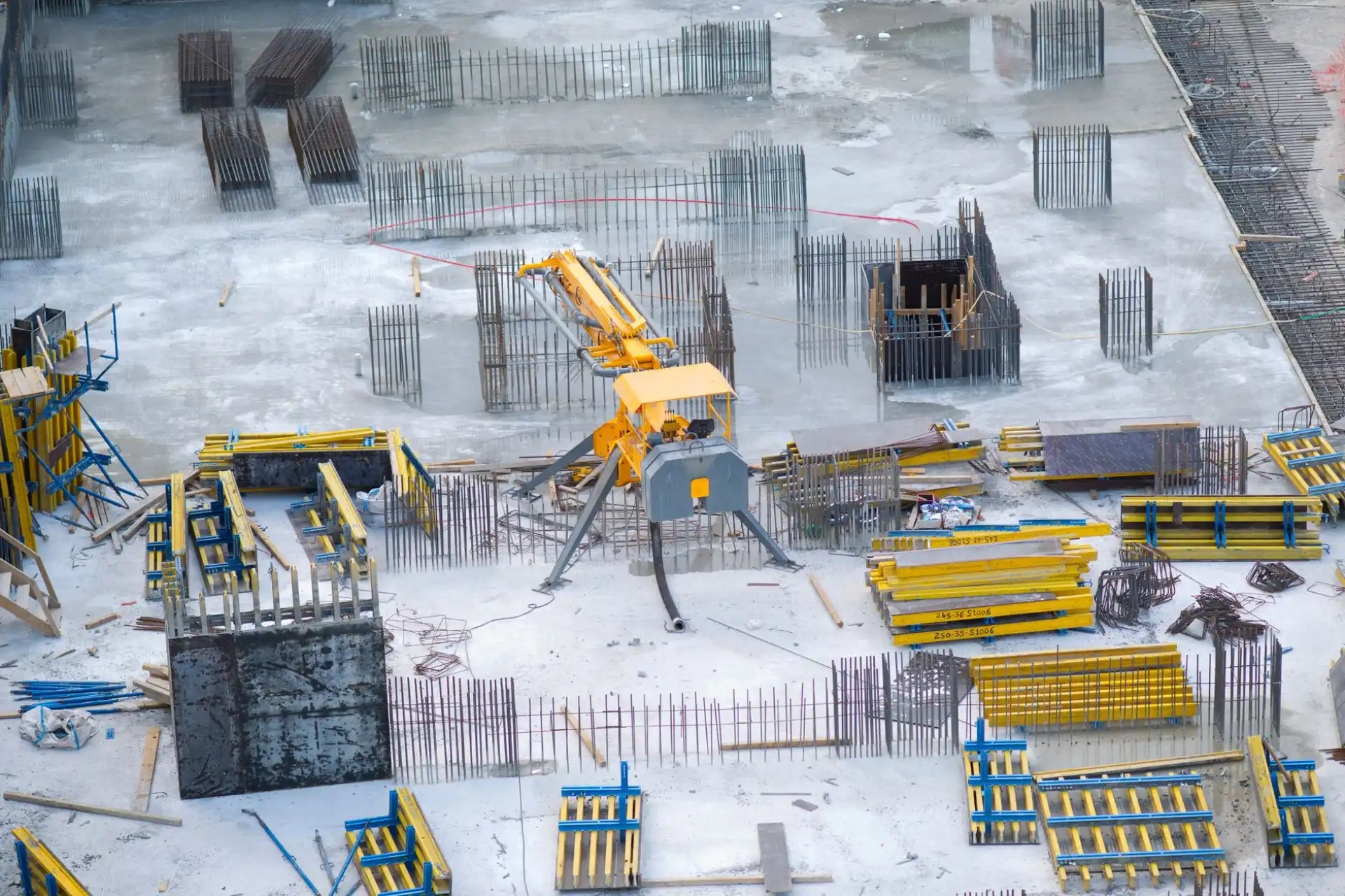 Aerial view of a foundation under construction, with reinforcing steel and yellow wall forms in place