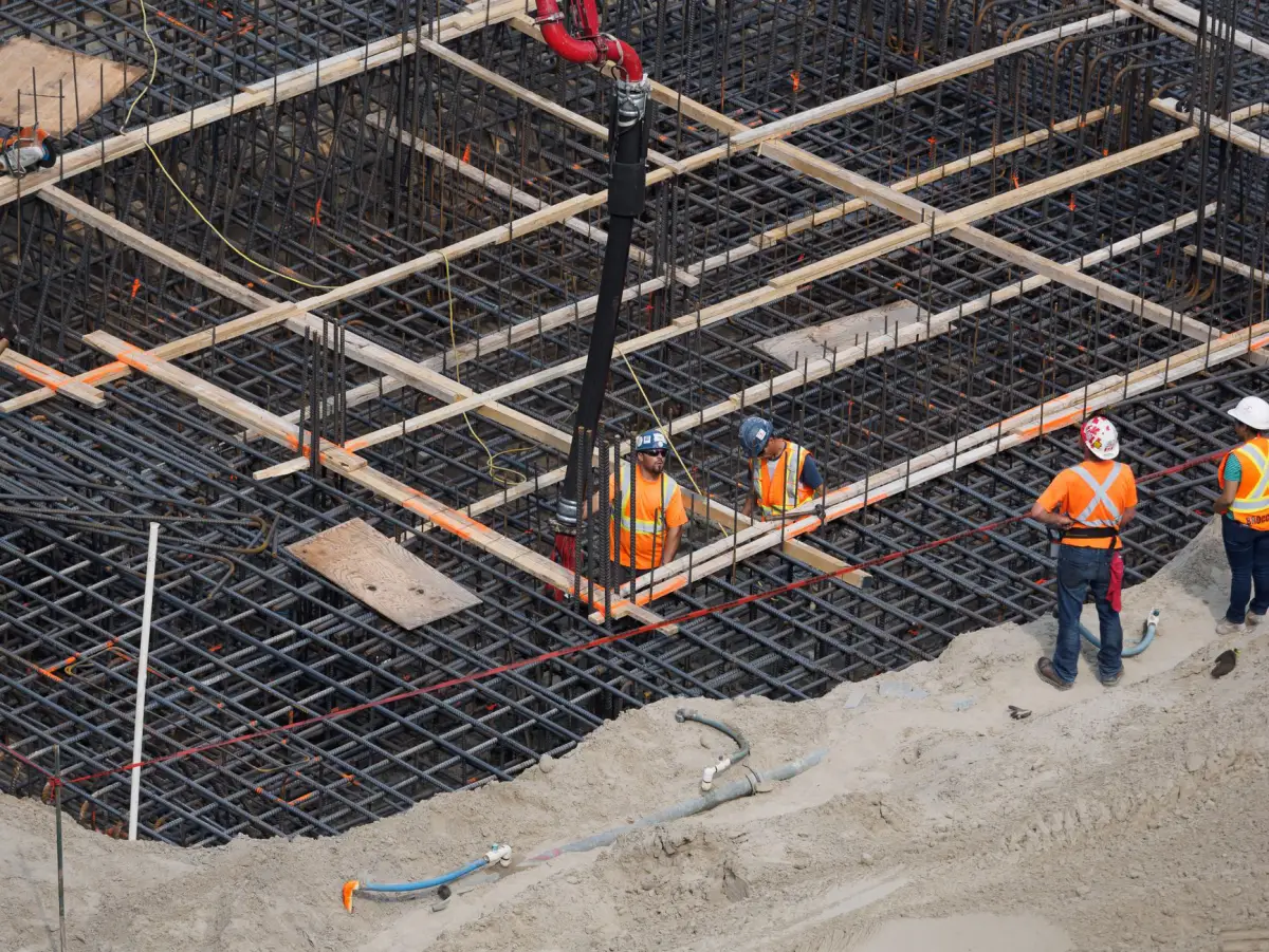 Reinforcing steel mat laid over a foundation excavation with a crane working above it