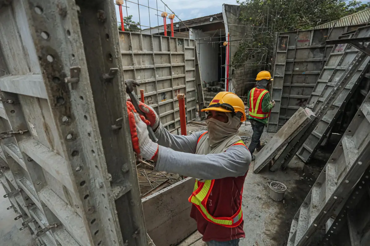 Workers in hard hats and high-visibility vests setting steel wall forms