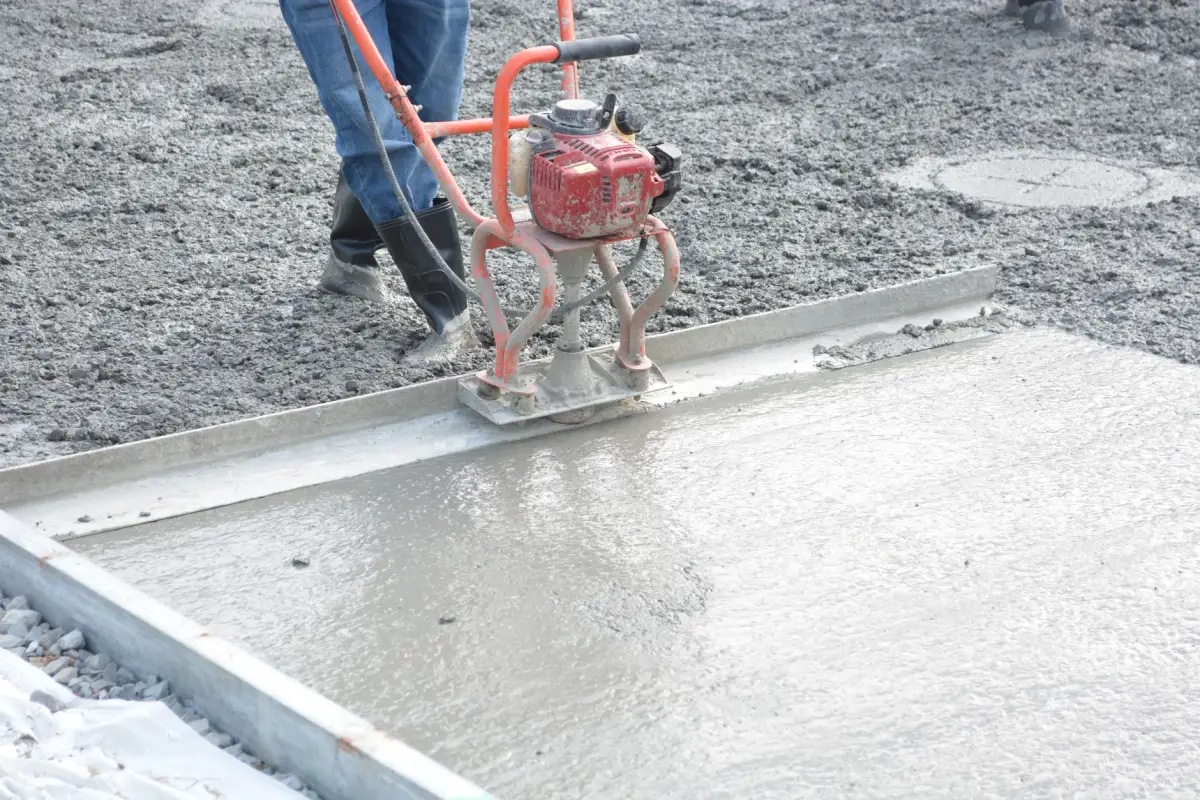 Power screed being worked across a strip of freshly placed concrete