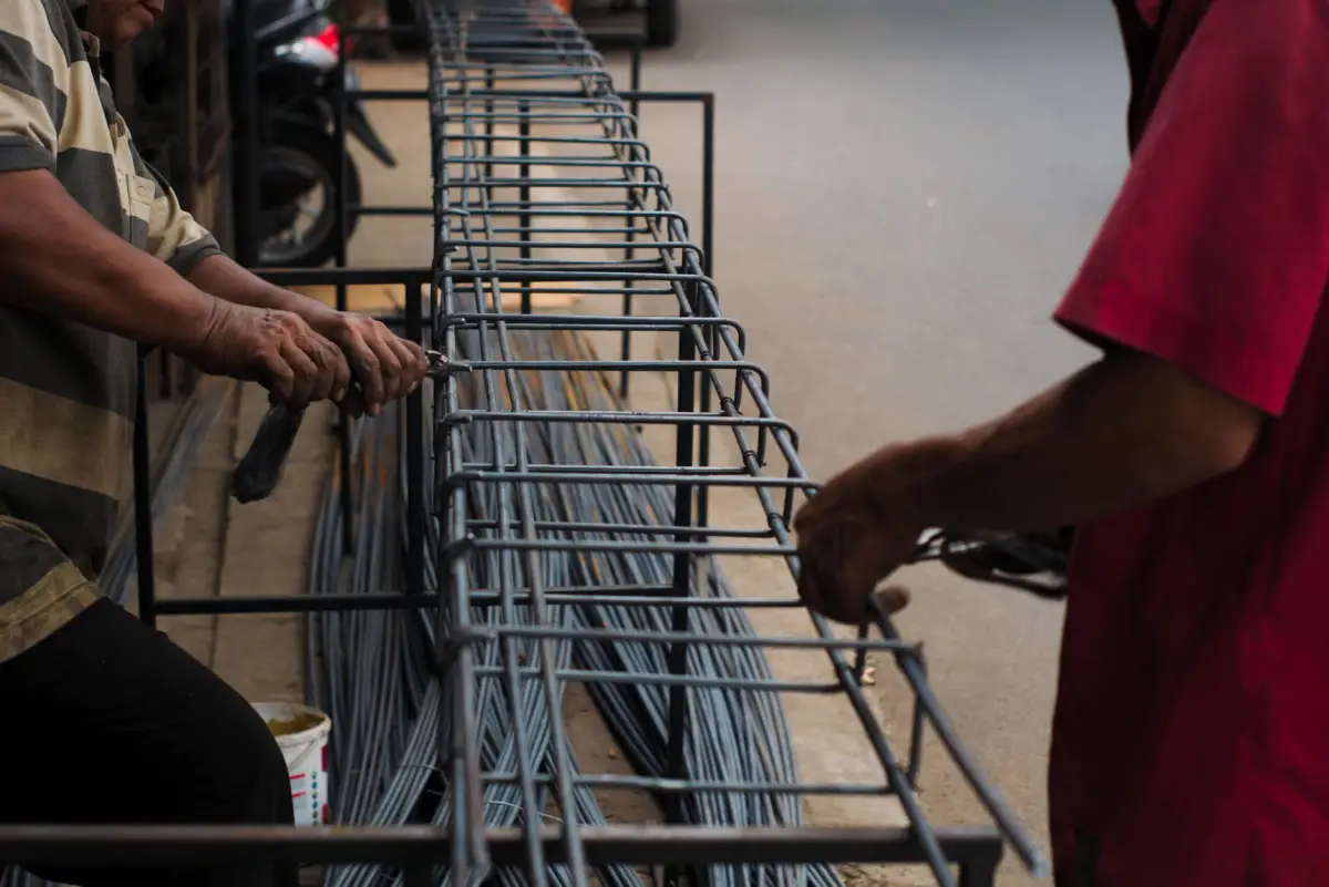 Hands tying a reinforcing steel cage with wire