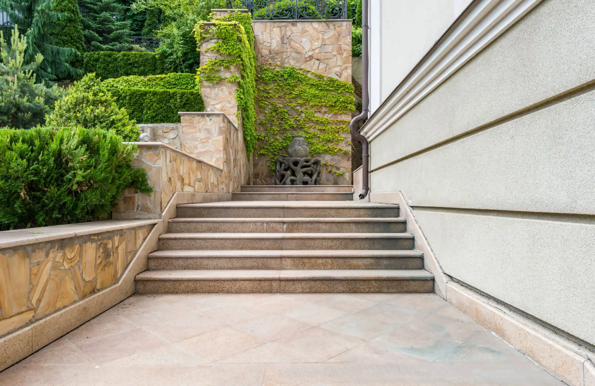 Wide concrete entry steps rising between planted terraces to a building entrance